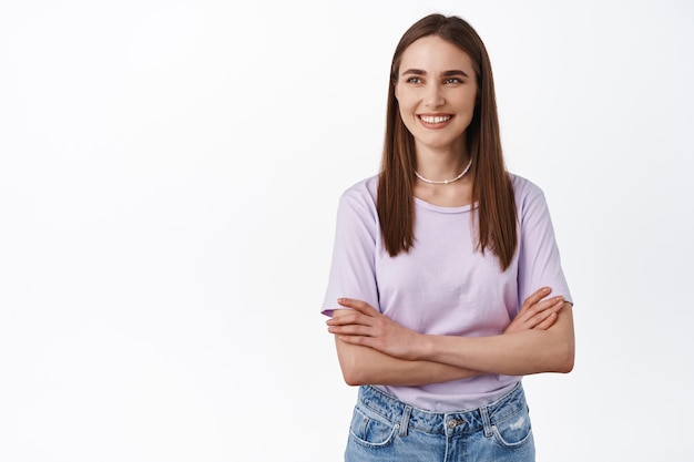 Fröhliches Mädchen mit kurzen natürlichen Haaren, sorglos lächelnd, Arme verschränkt, nach links auf das Banner-Logo schauend, Werbetext beiseite lesend, weißer Hintergrund