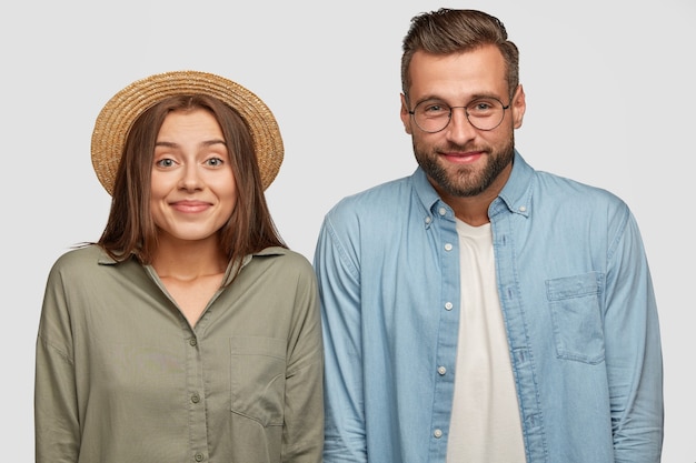 Fröhliches reizendes Paar, das gegen die weiße Wand aufwirft