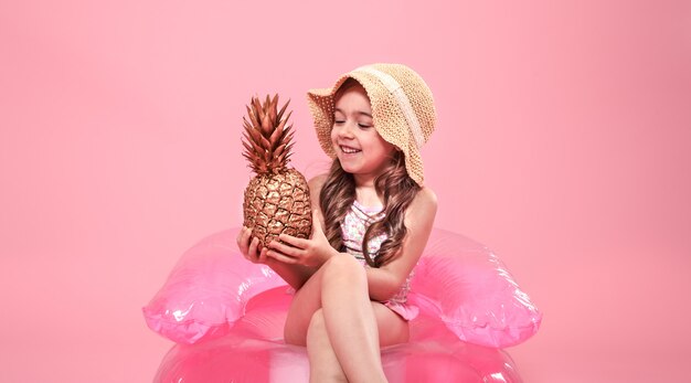fröhliches Sommermädchen mit Ananas auf farbigem Hintergrund