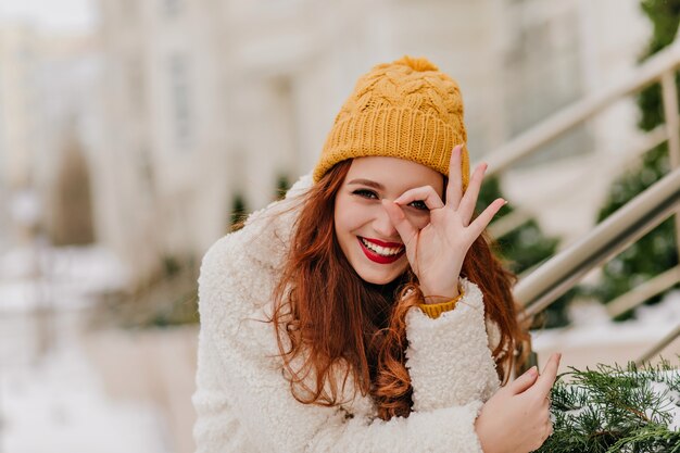 Fröhliches weibliches Modell, das Spaß im Winter hat. Erfreute kaukasische Ingwerfrau, die über Natur lacht.