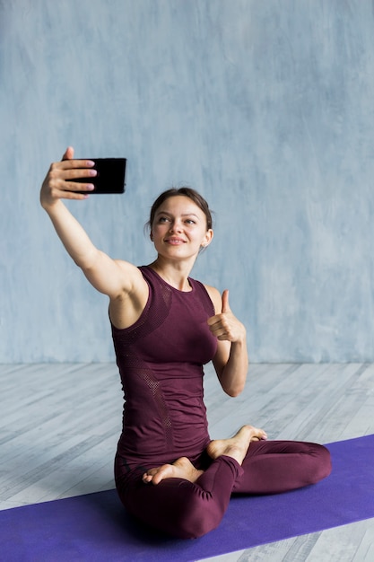 Frohe Frau, die ein Foto auf ihrer Yogasitzung macht