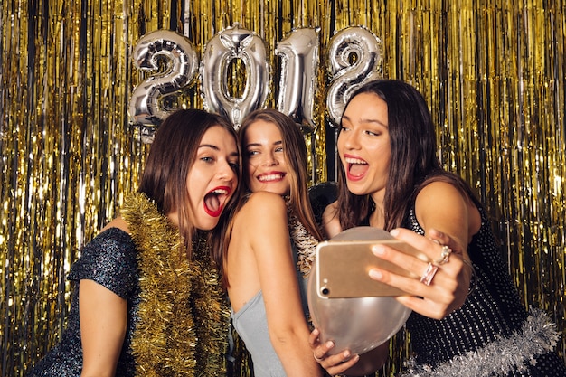 Frohe Mädchen, die selfie auf Neujahrsparty nehmen