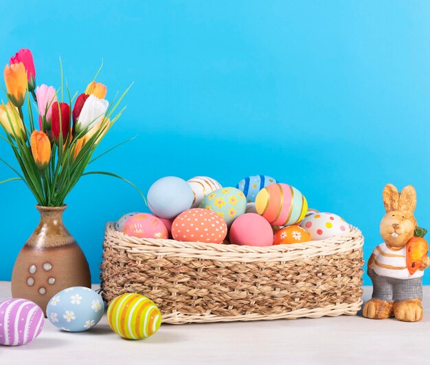 Frohe Ostern Ostern bemalte Eier im Korb auf rustikalem Holztisch für Ihre Dekoration im Urlaub