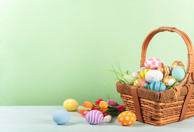 Frohe Ostern Ostern bemalte Eier im Korb auf rustikalem Holztisch für Ihre Dekoration im Urlaub