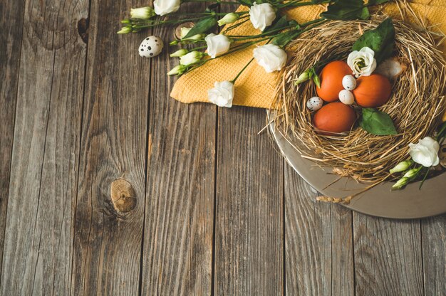 Frohe Ostern Tisch. Ostereier in einem Nest auf einer Metallplatte auf einem Holztisch. Frohe Ostern Konzept