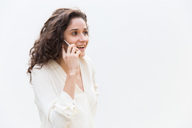 Frohe positive Frau, die auf Mobiltelefon spricht