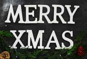 Kostenloses Foto frohe weihnachten inschrift mit grünen zweigen