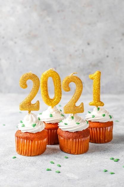 Frohes Neues Jahr 2021, Cupcakes mit goldenen Kerzen.