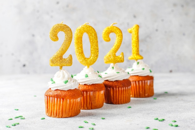 Frohes Neues Jahr 2021, Cupcakes mit goldenen Kerzen.