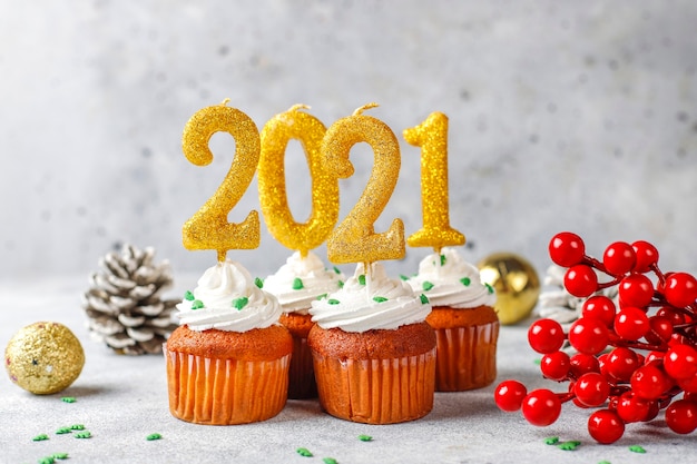 Frohes Neues Jahr 2021, Cupcakes mit goldenen Kerzen.