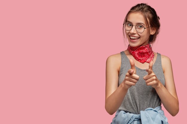 Frohes zufriedenes junges Weibchen mit dunklem gekämmtem Haar, trägt optische Brille