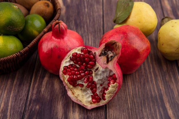 Frontalansicht Granatäpfel mit Birnen und Mandarinen auf Holzwand