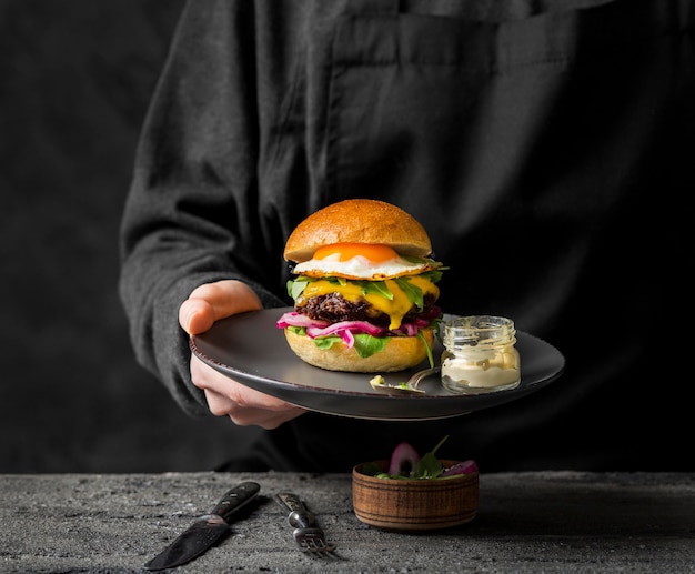 Frontansicht einer Person, die einen Teller mit Burger hält