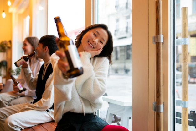 Frontansicht: lächelnde Frau mit Kombucha-Flasche