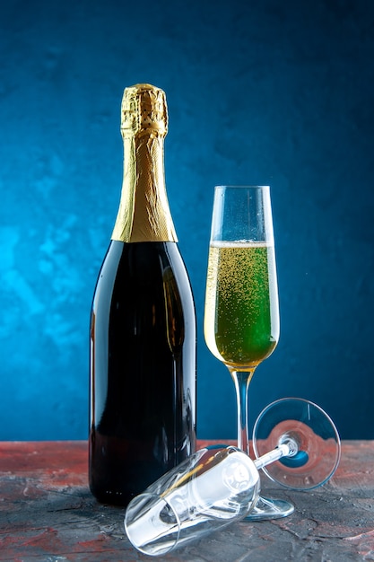 Frontansichtglas Champagner mit Flasche auf blauem Feierpartygetränk Alkoholfotofarbe neues Jahr