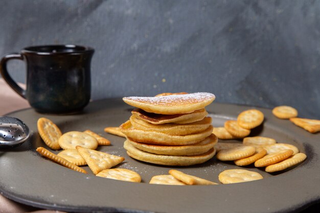 Frotn Ansicht Pfannkuchen und Cracker mit Tasse Milch auf dem grauen Hintergrund Frühstück Essen Mahlzeit süß
