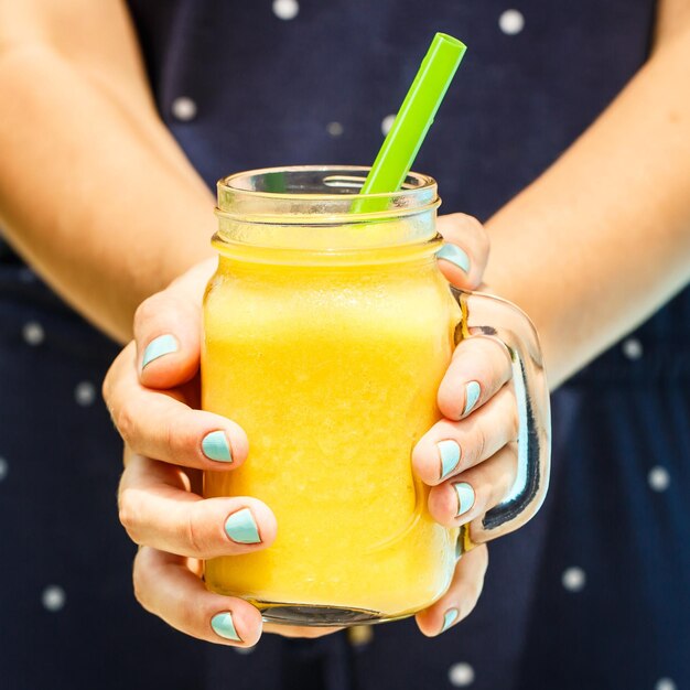 Frucht-Smoothie-Konzept für gesunde Ernährung Nahaufnahme von Detox-Smoothie mit Mango Frauenhand, die Smoothies hält