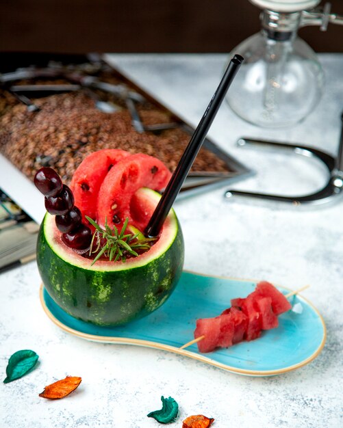 Fruchtcocktail in einer Wassermelone mit Kirschen und einem Strohhalm