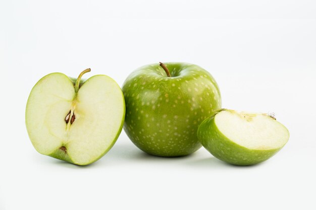 Fruchtfrisch milder saftiger grüner Apfel halb geschnitten und Stücke auf weißem Boden