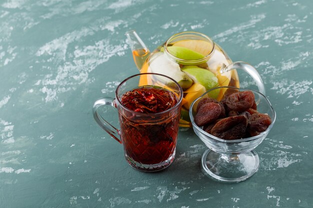 Fruchtgetränktes Wasser mit getrockneten Aprikosen, Kräutertee in einer Teekanne auf Gipsoberfläche