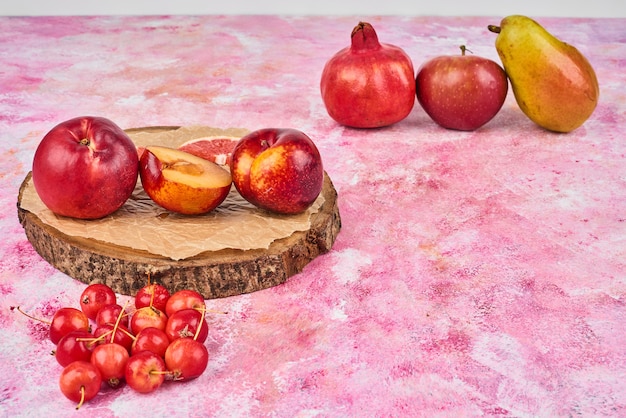 Früchte auf Holzbrett auf rosa.