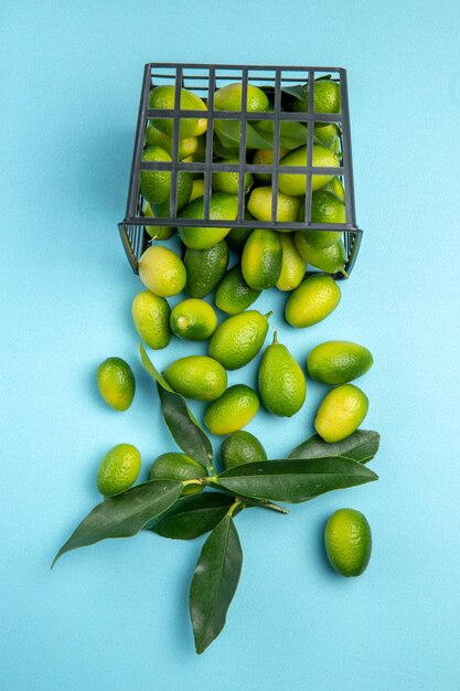 Früchte grüne Früchte mit Blättern im grauen Korb auf dem blauen Tisch