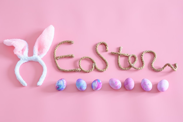 Frühling Ostern festlich. Oster kreative Inschrift auf Rosa mit Gegenständen des Osterdekors.