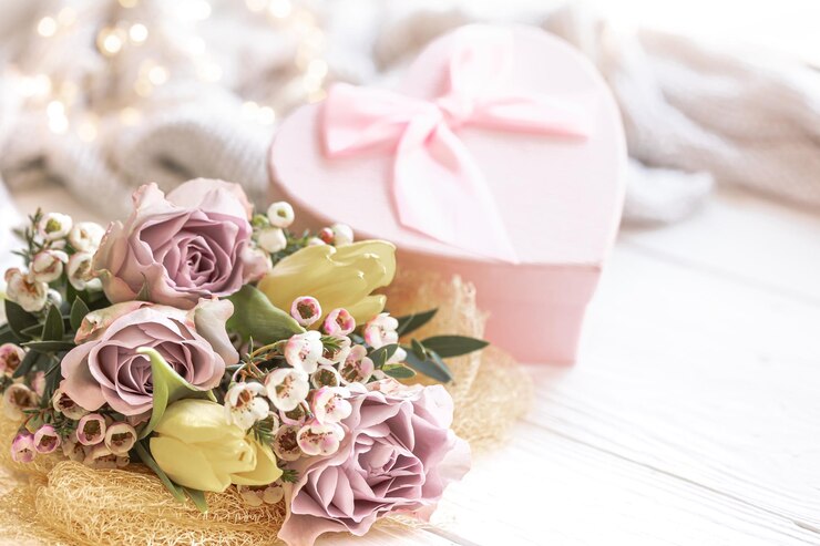 Kostenlose Foto frühlingskomposition mit blumen und einer geschenkbox auf verschwommenem hintergrund
