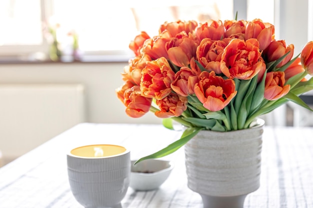 Kostenloses Foto frühlingskomposition mit einem strauß orangefarbener tulpen im inneren des hauses