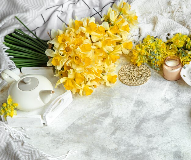Frühlingsstillleben mit einer Tasse Tee und Blumen. Heller Hintergrund, blühendes und gemütliches Haus.
