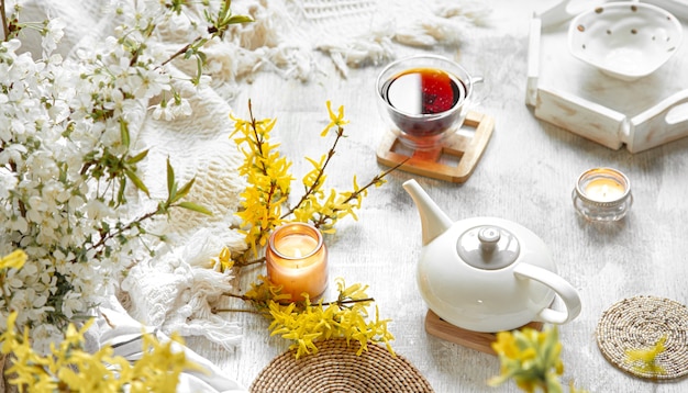 Frühlingsstillleben mit einer Tasse Tee und Blumen. Heller Hintergrund, blühendes und gemütliches Haus.