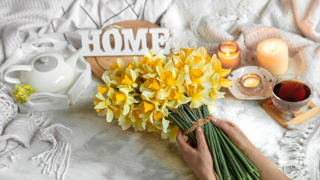 Frühlingsstillleben mit einer Tasse Tee und Blumen. Heller Hintergrund, blühendes und gemütliches Haus.