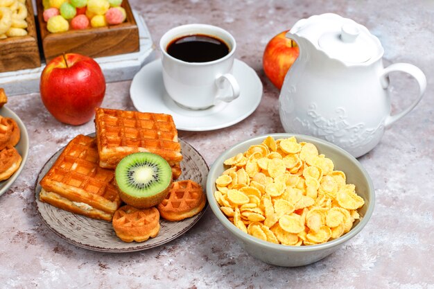 Kostenloses Foto frühstück mit verschiedenen süßigkeiten, waffeln, cornflakes und einer tasse kaffee, draufsicht