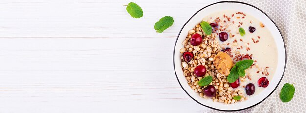 Frühstück. Schüssel hausgemachtes Müsli mit Bananenpüree und frischen Beeren. Sitzordnung bei Tisch. Gesundes Essen. Draufsicht.