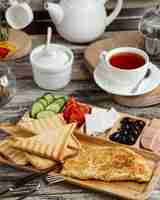 Kostenloses Foto frühstücksaufbau mit omelett-toast-gurken-tomaten-käse-oliven und tee