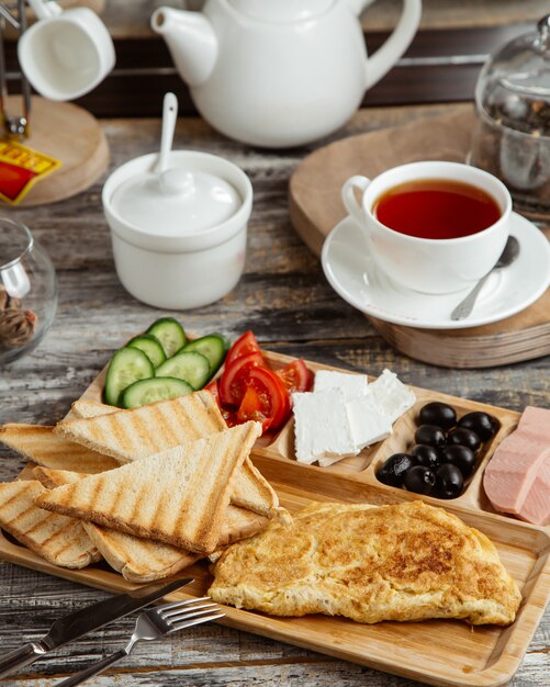 Frühstücksaufbau mit Omelett-Toast-Gurken-Tomaten-Käse-Oliven und Tee