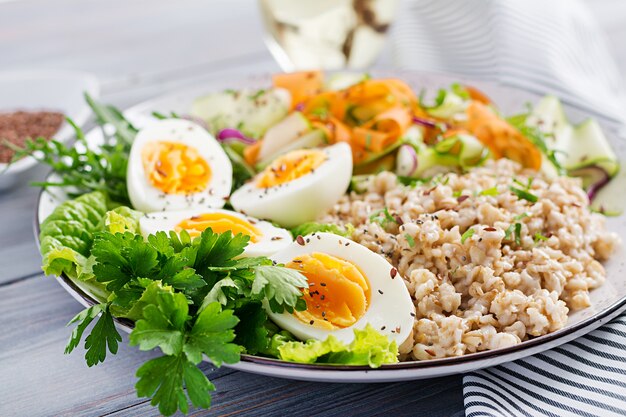 Frühstücksschüssel mit Haferflocken, Zucchini, Salat, Karotte und gekochtem Ei