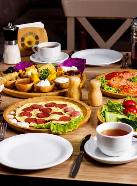 Frühstücksset mit Rührei mit Würstchen, frischem Salatkäse und einer Tasse Tee