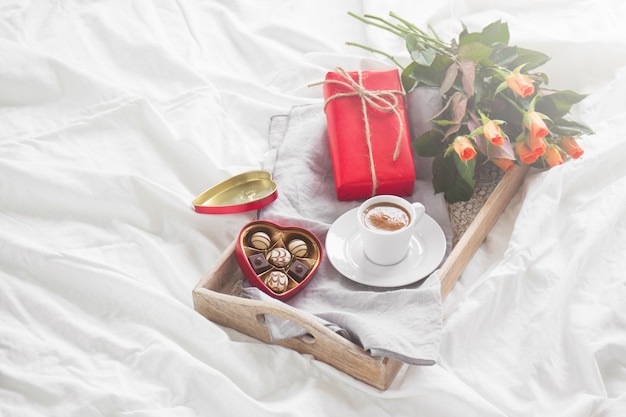Frühstückstablett mit einem Geschenk, Blumen und Pralinen