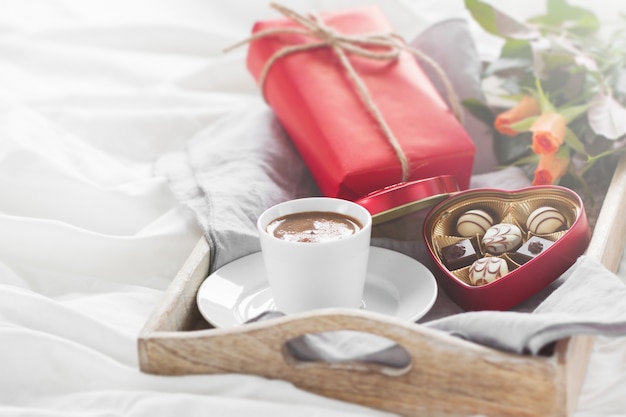 Frühstückstablett mit einem geschenk, blumen und pralinen