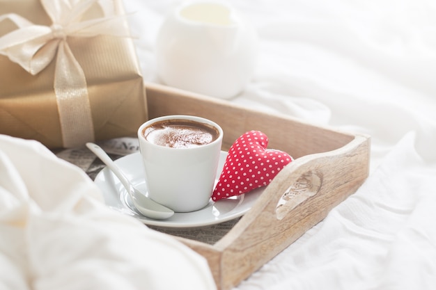 Frühstückstablett mit einem Kaffee, einem Herzen und einem goldenen Geschenk