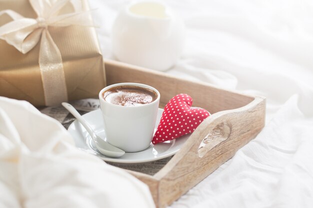 Frühstückstablett mit einem Kaffee, einem Herzen und einem goldenen Geschenk