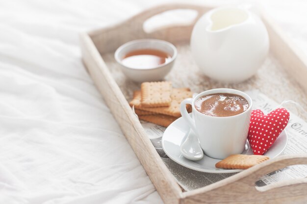 Frühstückstablett mit einem Kaffee, einem Herzen und einem goldenen Geschenk