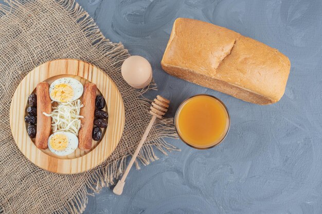 Frühstücksteller mit Saft und Brot auf Marmortisch.