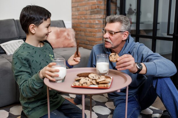 Frühstückszeit, Großvater und Enkel beim Morgenfrühstück mit Milch und Keksen.