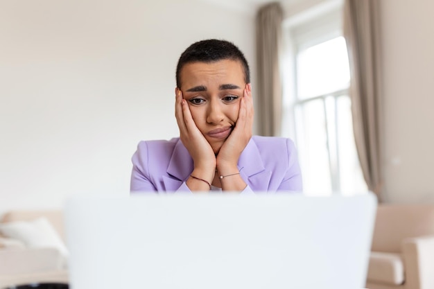 Frustrierte junge afroamerikanische Geschäftsfrau, die an einem Laptop arbeitet und am Schreibtisch im Büro sitzt