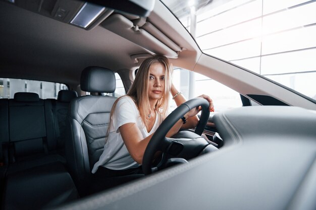 Fühlt sich müde. Mädchen im modernen Auto im Salon. Tagsüber drinnen. Neues Fahrzeug kaufen