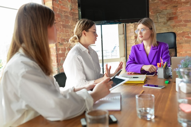 Führer. Junge kaukasische Geschäftsfrau im modernen Büro mit Team. Treffen, Aufgaben geben. Frauen im Front Office arbeiten.