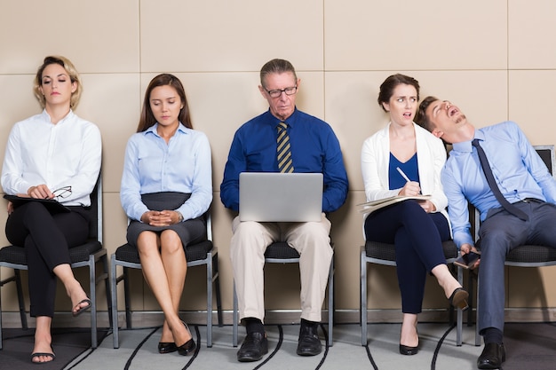 Kostenloses Foto fünf bored business-leute sitzen im wartezimmer