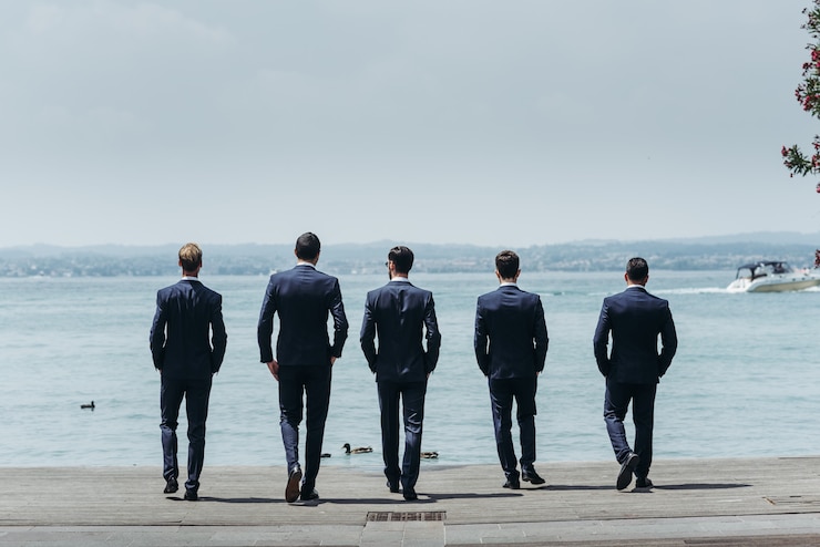 Kostenlose Foto fünf männer in eleganten anzügen gehen auf das blaue meer zu